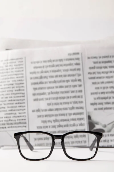 Mise au point sélective de lunettes noires et de journaux sur fond noir et blanc — Photo de stock