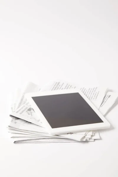 Tablet digitale con schermo bianco su pile di giornali, su bianco — Foto stock
