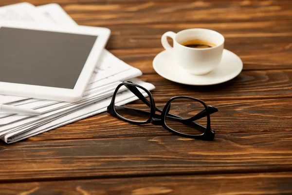 Xícara de óculos de café, tablet digital e pilha de jornais em fundo de madeira — Fotografia de Stock