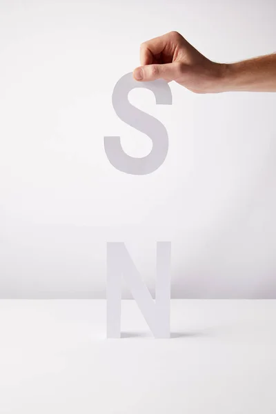 Cropped view of person holding paper letters - n and s, on white background — Stock Photo