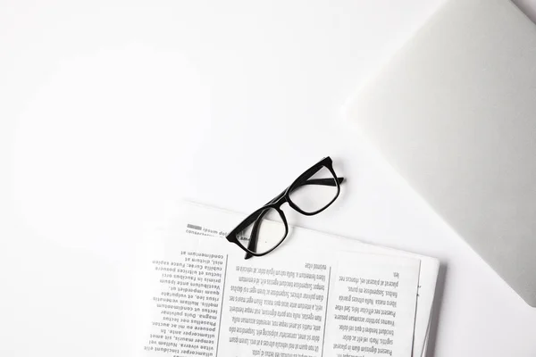 Top view of eyeglasses, laptop and newspapers on white table — Stock Photo