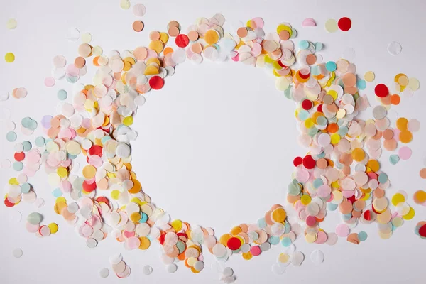 Vue de dessus du cercle de morceaux de confettis colorés sur la surface blanche — Photo de stock