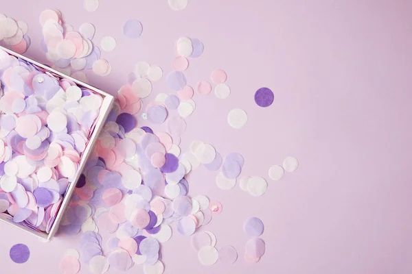 Vista superior de peças de confete em caixa de papel e na superfície violeta — Fotografia de Stock