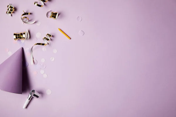 Vue de dessus du chapeau de fête et des morceaux de confettis sur la surface violette — Photo de stock