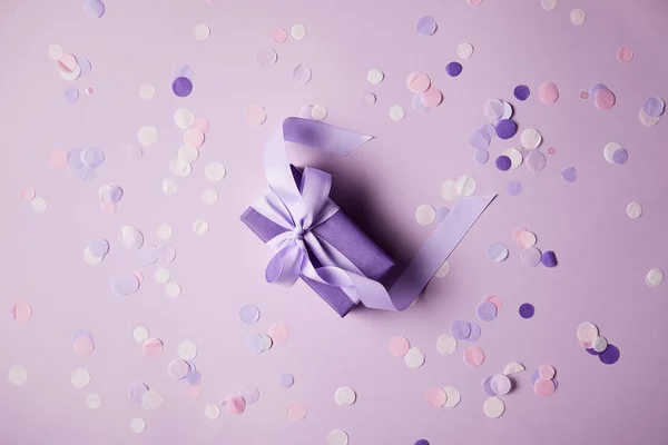 Vue de dessus d'une boîte cadeau violette et des morceaux de confettis sur la surface — Photo de stock