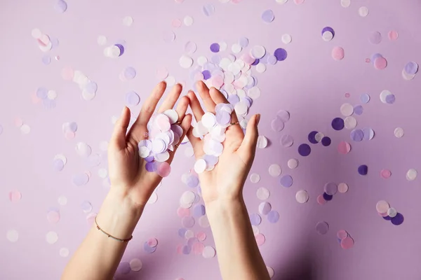 Cropped image of woman holding falling confetti pieces on surface — Stock Photo