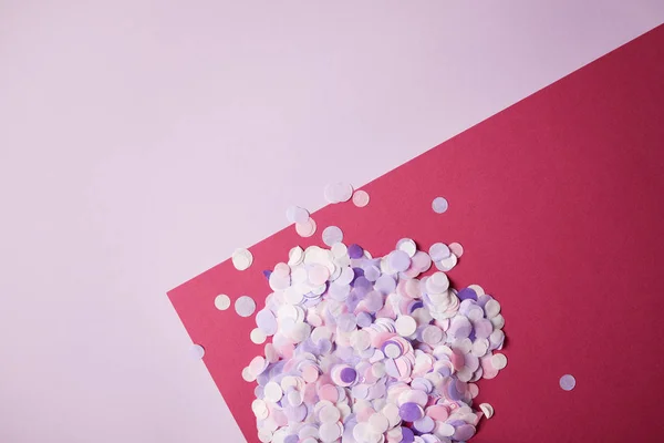 Вид зверху на шматочки конфетті на червоній і фіолетовій поверхні — стокове фото