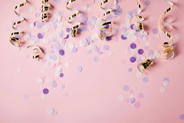 Vue de dessus des morceaux de confettis violets sur la surface rose — Photo de stock