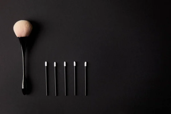 Vista dall'alto di un grande e cinque piccoli pennelli per il trucco su sfondo nero — Foto stock