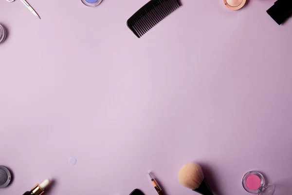 Vue de dessus de divers outils de maquillage et cosmétiques sur fond violet — Photo de stock