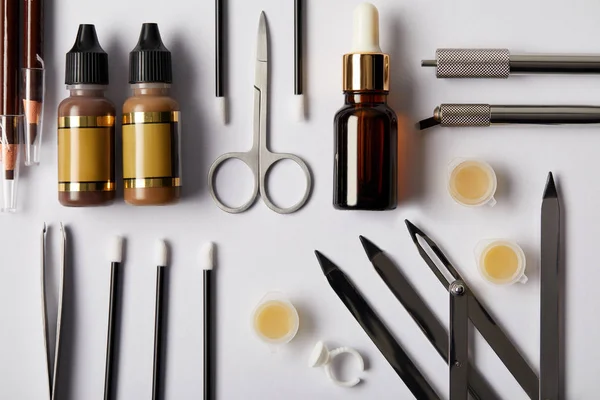 Draufsicht auf verschiedene Werkzeuge und Kosmetika für dauerhaftes Make-up auf Weiß — Stockfoto