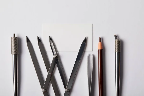 Top view of various tools for permanent makeup and blank card on white — Stock Photo