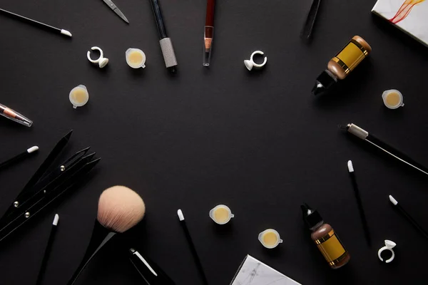 Vue du dessus des outils pour le maquillage permanent sur table noire dans le salon — Photo de stock