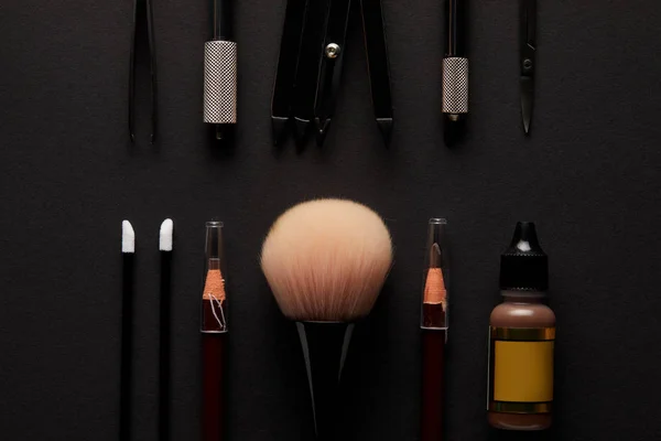 Flache Lage von Bleistiften und Pinseln für dauerhaftes Make-up isoliert auf schwarz — Stockfoto