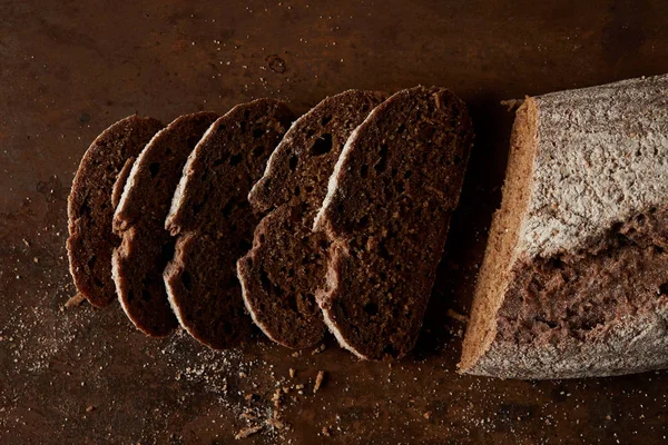 Elevated view of bred and slices of bread on rustic metal tabletop — Stock Photo