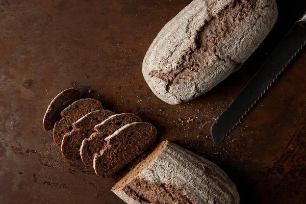 Draufsicht auf Brot, Scheiben und Messer auf rostigem Metalltisch — Stockfoto