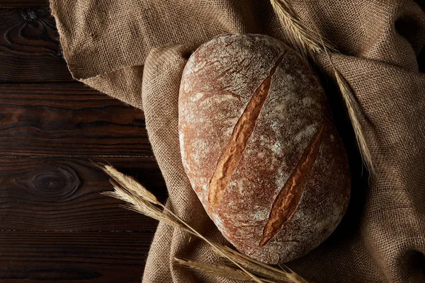 Vista superior de pan, trigo y saco sobre mesa de madera rústica - foto de stock