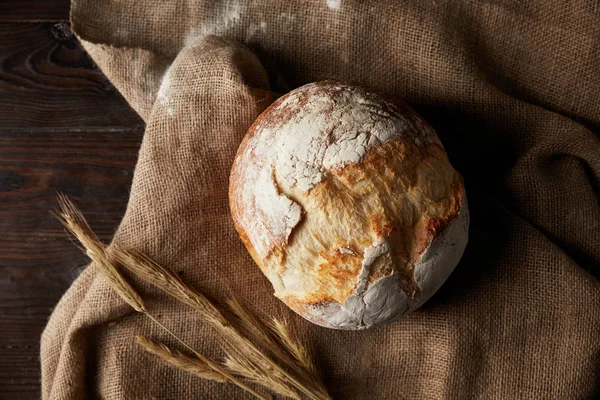 Vista dall'alto di pane, frumento, sacco ricoperto da farina su tavola di legno — Foto stock