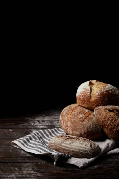 Imagen de primer plano de varios tipos de pan y saco en la cubierta de mesa de madera por harina - foto de stock