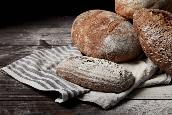 Closeup image of various types of bread, flour and sackcloth on wooden table — Stock Photo