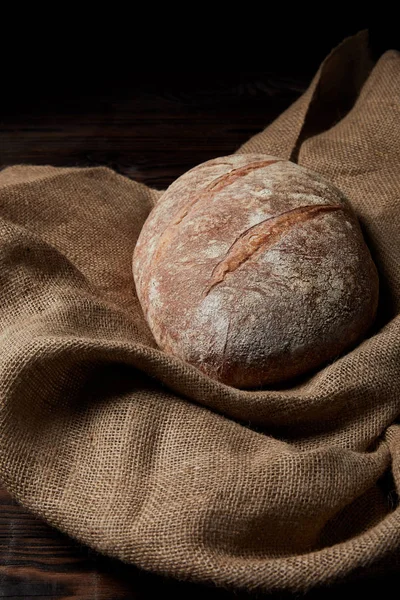 Closeup image of bread and sackcloth on rustic wooden table — Stock Photo