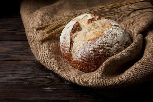 Imagen de primer plano de pan, trigo y saco en la mesa de madera rústica - foto de stock
