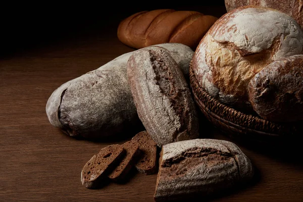 Закрыть изображение различных видов хлеба и плетеной корзины на деревянном столе — стоковое фото