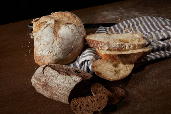 Primo piano di vari tipi di pane, sacco e tagliere sul tavolo — Foto stock