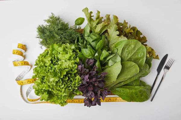 Vue de dessus de divers légumes mûrs en boîte avec couverts et ruban à mesurer sur surface blanche — Photo de stock