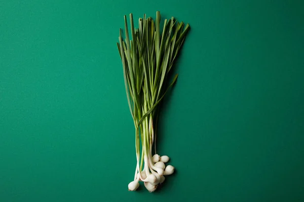 Vue du dessus du bouquet de tiges d'ail sur la surface verte — Photo de stock