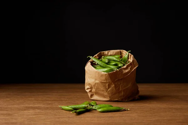 Bolsa de papel de vainas de guisantes en la mesa de madera - foto de stock