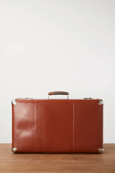 Закрытый кожаный чемодан на деревянном фоне — стоковое фото