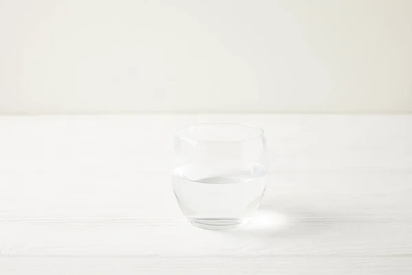 Primer plano plano de un solo vaso de agua en la mesa de madera blanca - foto de stock