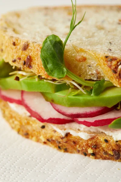 Primo piano di panino vegetariano con fette di ravanello mature e germogli di piselli sul tagliere di legno — Foto stock