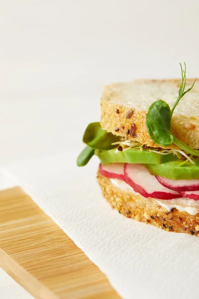 Primer plano de bocadillo con rodajas de rábano y brotes de guisante en la tabla de cortar de madera - foto de stock