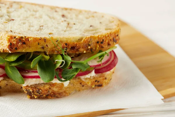 Primer plano de bocadillo fresco con rodajas de rábano y brotes de guisantes en la tabla de cortar de madera - foto de stock