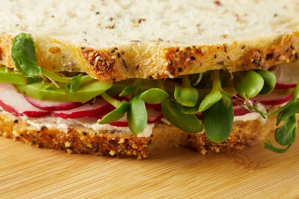 Primo piano di panino vegetariano con fette di ravanello e germogli di piselli sulla superficie di legno — Foto stock