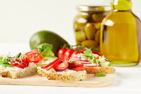 Close-up shot of delicious various sandwiches on cutting board with avocado and olive oil — Stock Photo