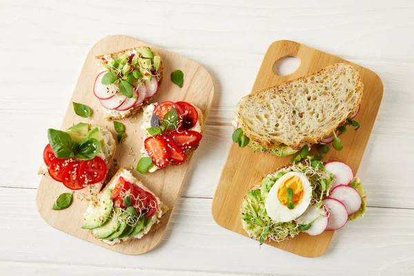 Top view of various delicious sandwiches on white wooden tabletop — Stock Photo