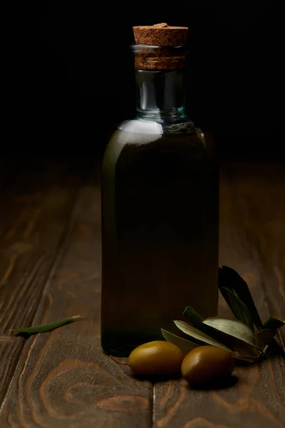 Bottiglia di saporito olio d'oliva con ramo su superficie di legno — Foto stock