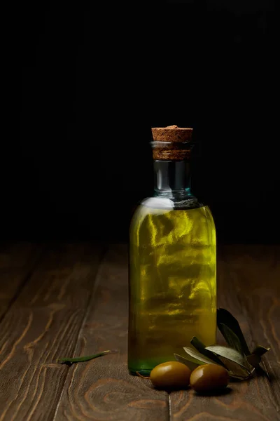 Flasche köstliches Olivenöl mit Zweig auf Holzoberfläche — Stockfoto