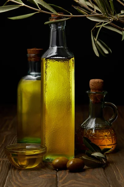 Bottles of various olive oil on wooden surface — Stock Photo