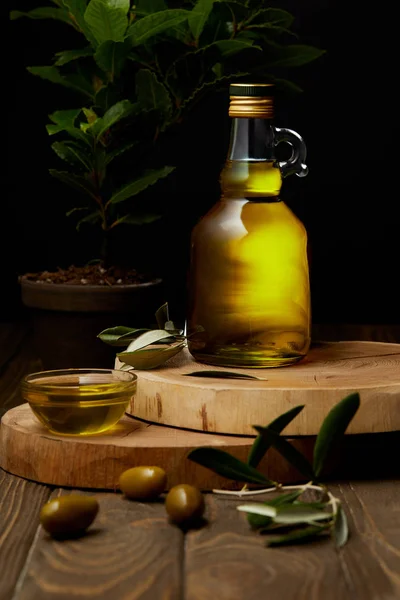 Aceite de oliva en botella y cuenco sobre tablas de madera - foto de stock