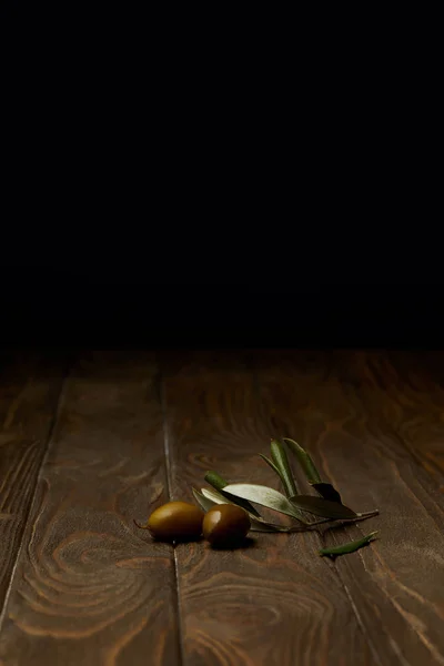 Оливковая ветвь с оливками на деревянной поверхности — стоковое фото