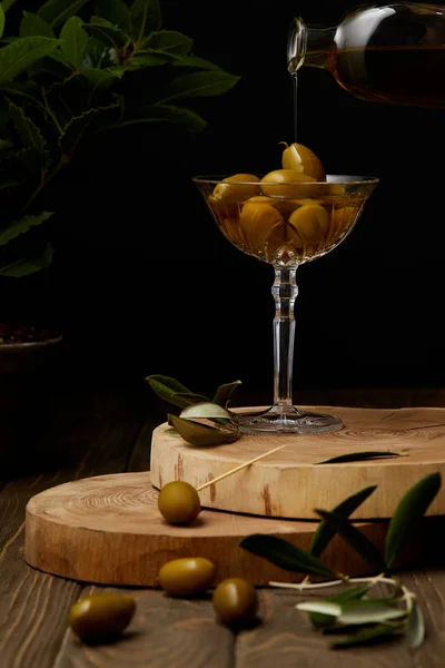 Vintage glass with olives and oil on stacked boards — Stock Photo