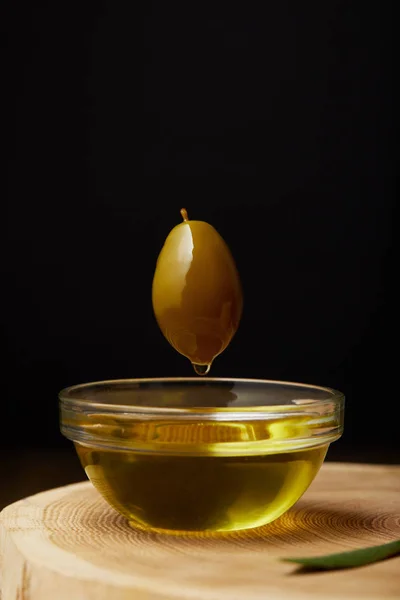 Oliven fliegen über Schüssel mit Öl auf Holzoberfläche — Stockfoto