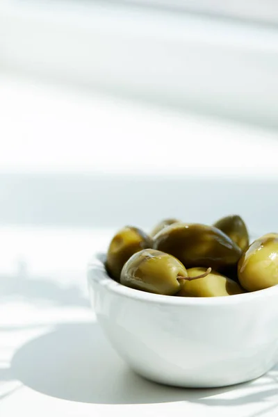 Nahaufnahme einer Schüssel mit grünen Oliven auf weißem Tisch — Stockfoto