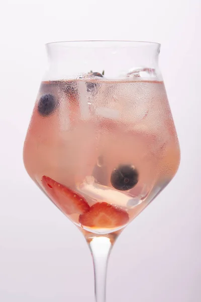 Close up shot of glass of lemonade with ice cubes, strawberries and blueberries isolated on grey background — Stock Photo