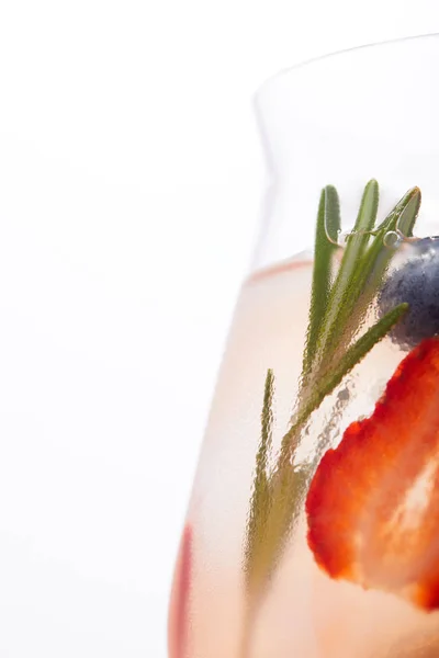 Partial view of glass of lemonade with rosemary, blueberry and strawberry isolated on white background — Stock Photo