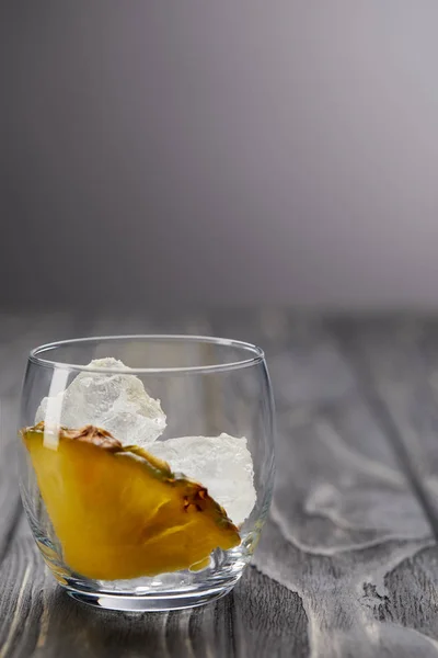 Vidro com cubos de gelo e pedaço de abacaxi na mesa de madeira cinza — Fotografia de Stock